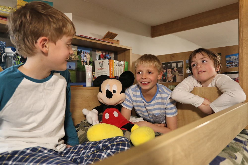three boys in pyjamas sitting on a bunk bed chatting