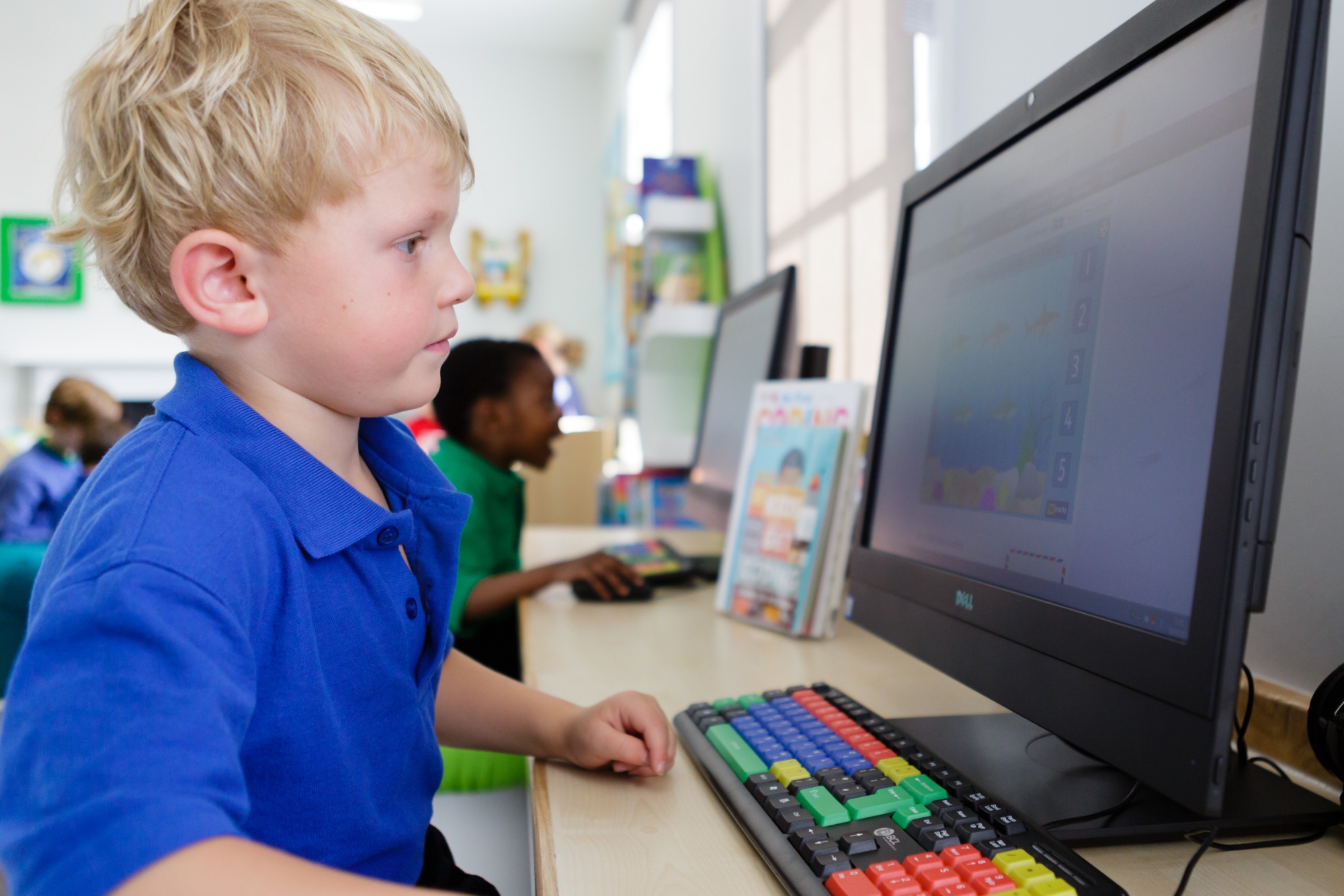 A young boy focused on a computer screen, engrossed in his work, showcasing his technological skills.