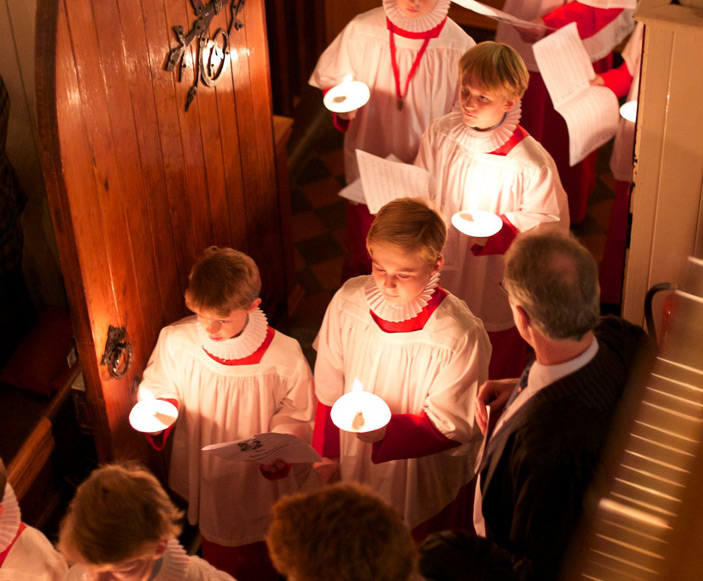 looking down on choir boys entering the chapel holding candles