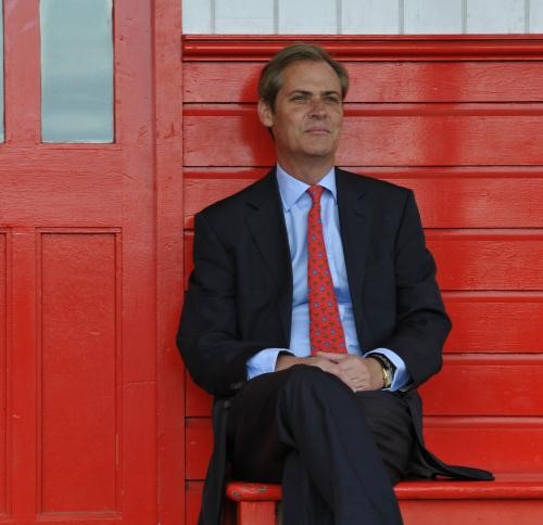 Man in a suit with a red tie sitting outside on a red bench