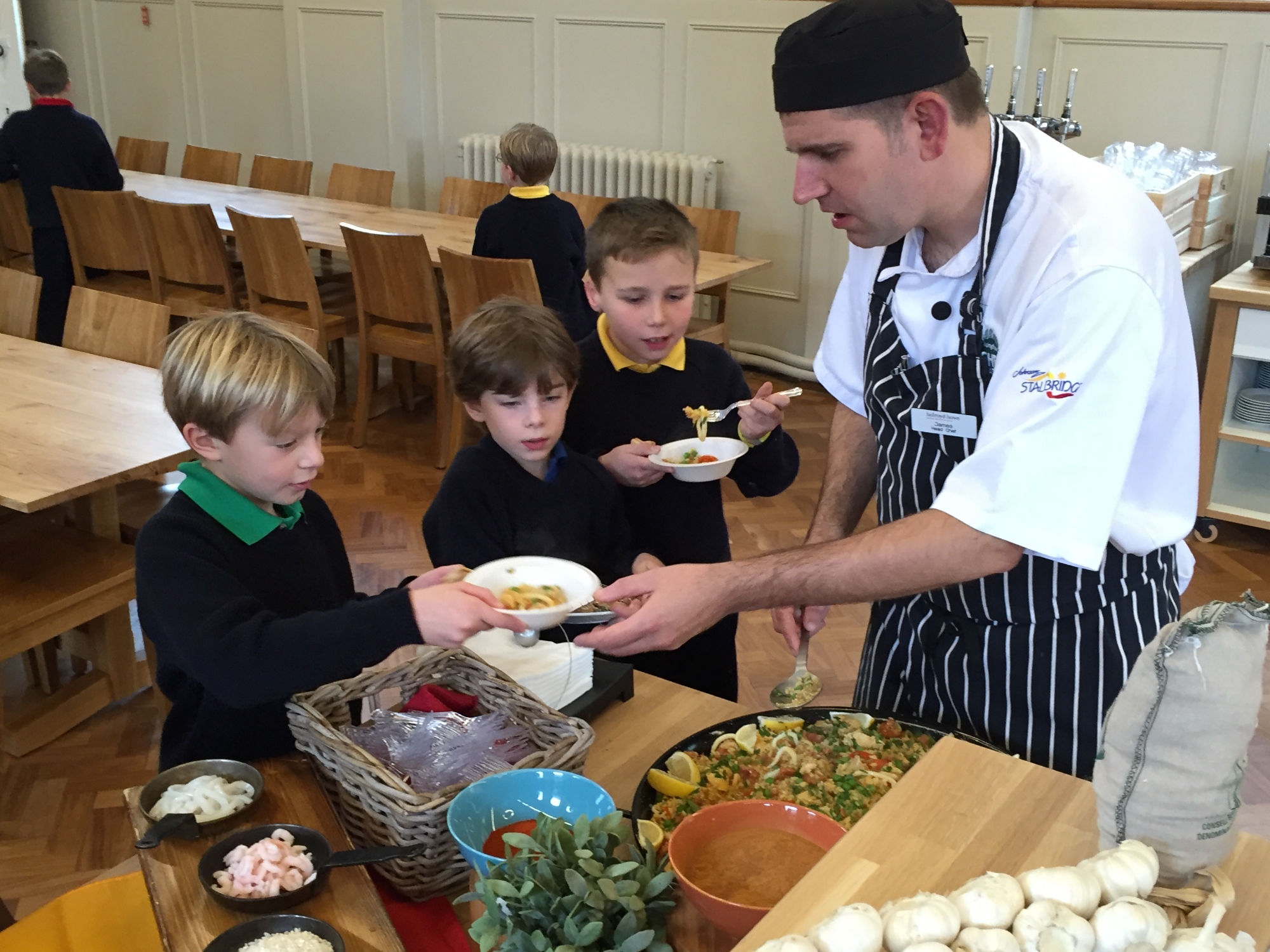 School chef serving food to three boys in the dining room