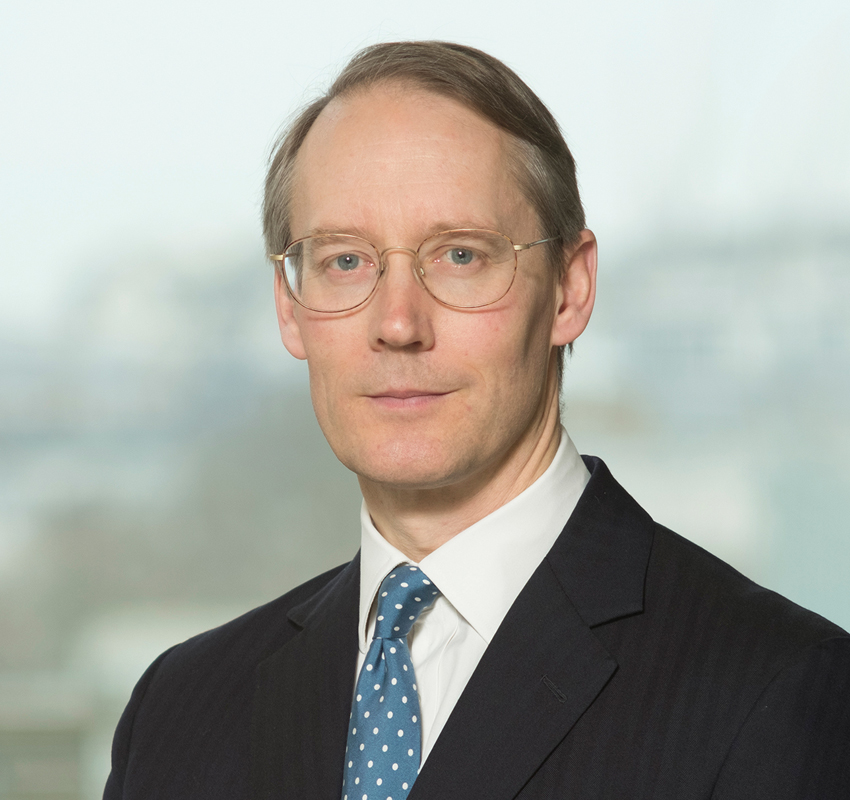 Man with grey hair and glasses wearing a suit