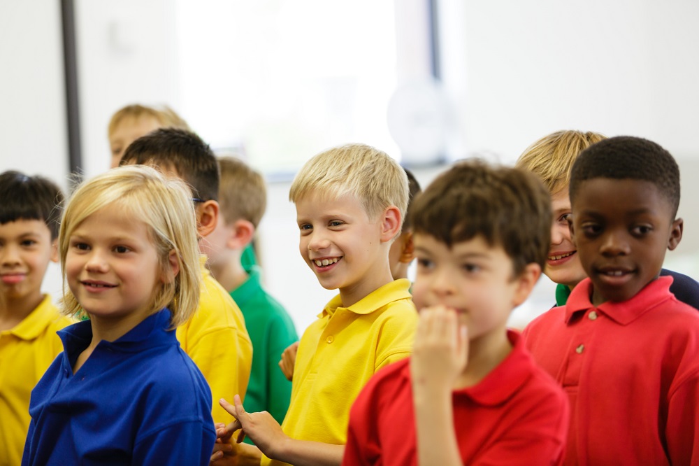 A classroom filled with children, one of whom is smiling brightly.