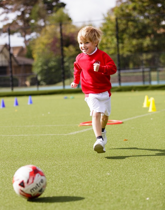 Young boys on astroturf running after a football