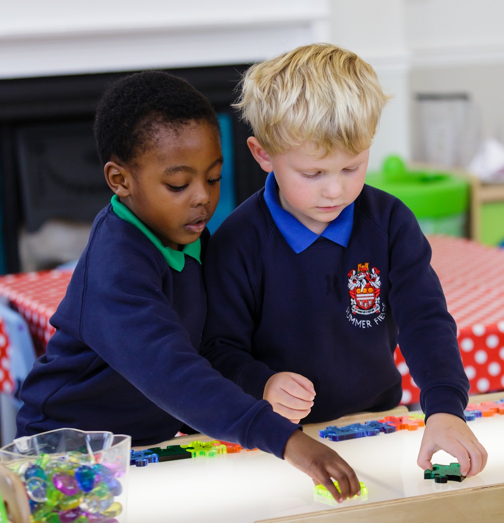 Two little boys playing with shapes on a lightbox