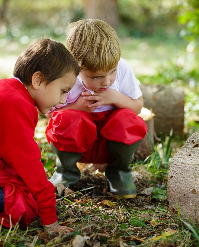Two young boys dressing in red outdoor clothing out in nature