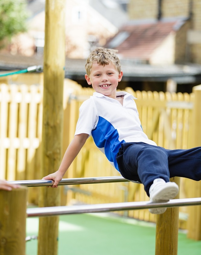 A young boy confidently performs a holds himself up on a bar, showcasing his strength and balance.